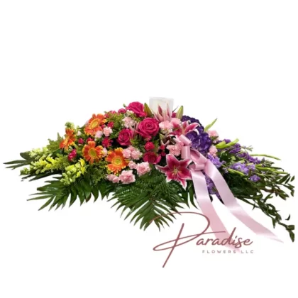 Celebration of Life Casket Spray featuring pink carnations, orange gerbera daisies, purple hydrangeas, hot pink roses, yellow snapdragons, stargazer lilies, purple stock, and green gladiolus.