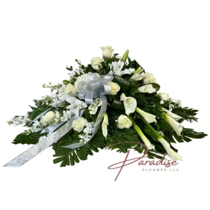 Celestial Tribute Casket Spray featuring white roses, stocks, lilies, calla lilies, and greenery in a serene arrangement.