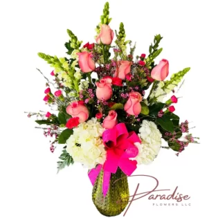 Cheers to Flowers bouquet featuring white snapdragons, hot pink roses, mini carnations, hydrangeas, and pink waxflowers with lush greenery.