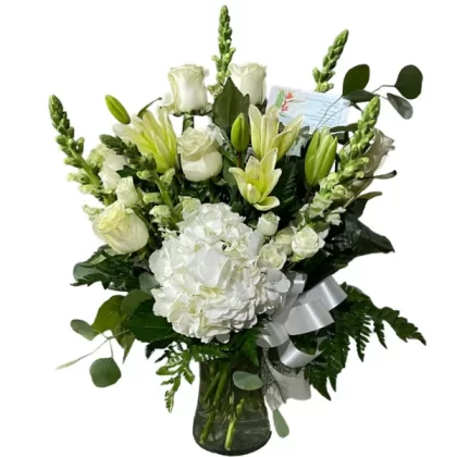 Classic Funeral Arrangement featuring white roses, lilies, hydrangeas, snapdragons, and lush greenery in a sleek cylinder vase.