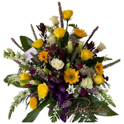 Colorful Funeral Bouquet featuring white snapdragons, safari flowers, purple mini carnations, sunflowers, white lilies, white and yellow roses, and waxflowers.