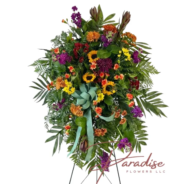 Colorful Standing Spray featuring sunflowers, yellow gladioli, purple snapdragons, orange carnations, mums, bells of Ireland, hypericum berries, and lush greenery.