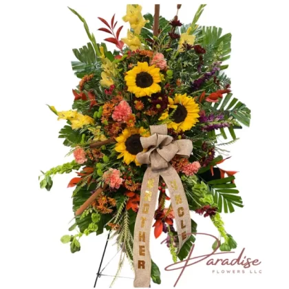 Colorful Standing Spray featuring sunflowers, yellow gladioli, purple snapdragons, orange carnations, mums, bells of Ireland, hypericum berries, and lush greenery.