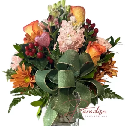 Cozy Harvest floral arrangement featuring orange roses, daisies, pink carnations, charmelias, peach stocks, red hypericum, and lush greenery.