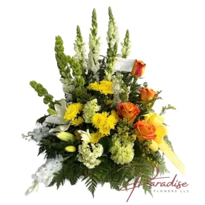 Eternal Sunshine floral arrangement featuring white snapdragons, stocks, lilies, yellow cushions, orange roses, green hydrangea, limonium, and greenery.