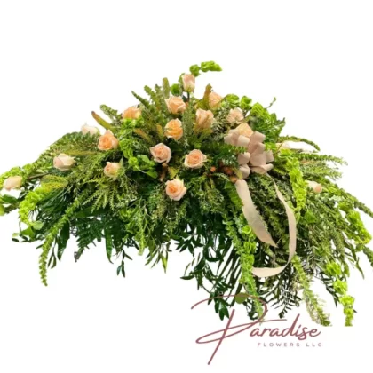 Garden Greens Casket Spray featuring delicate peach roses and lush greenery including ferns, eucalyptus, and ivy.