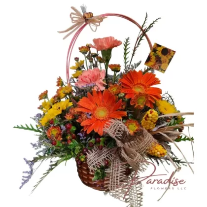 Happy Basket floral arrangement featuring orange carnations, gerbera daisies, yellow cushion poms, and hypericum berries.