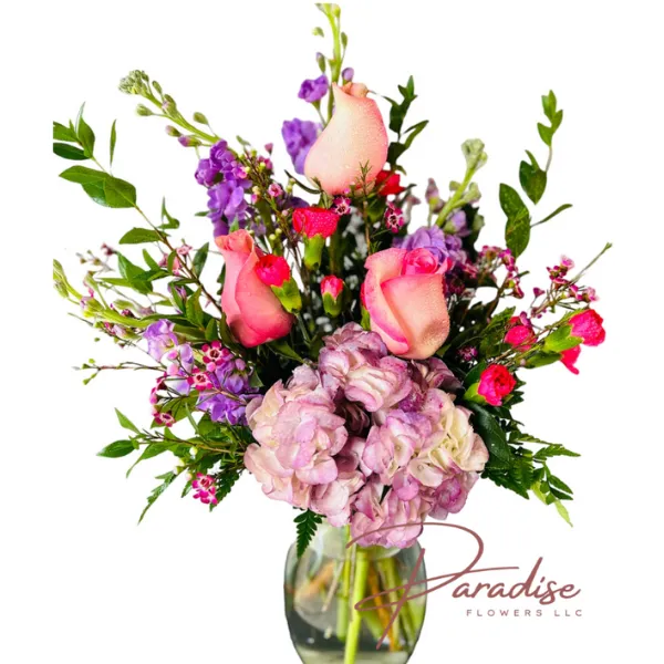 Happy Day bouquet featuring pink roses, purple stocks, hot pink carnations, purple hydrangea, and waxflowers with lush greenery.