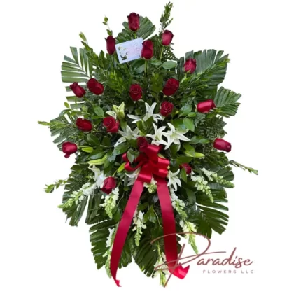 Heavenly Sentiments standing spray featuring red roses, white snapdragons, white lilies, and lush greenery.