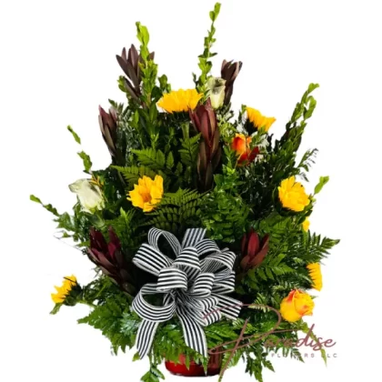 Majesty's Fall Elegance floral arrangement featuring white and orange roses, sunflowers, Safari Sunset blooms, and lush greenery in a red ceramic vase.