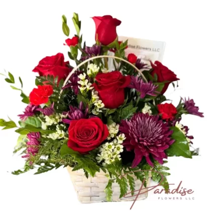 Passion floral arrangement featuring red roses, chrysanthemums, mini carnations, wax-flowers, and lush greenery in vibrant red hues.