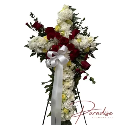 Peaceful Cross standing spray with white roses, hydrangeas, yellow and red spray roses, and white and red carnations for a funeral tribute.