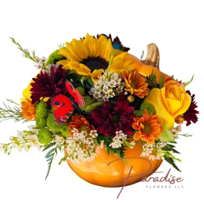 Perfect Pumpkin floral arrangement featuring yellow roses, daisies, purple mums, sunflowers, and green button details nestled in a ceramic pumpkin vessel.