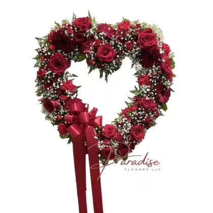 Red Heart of Love standing spray with red roses, carnations, mini carnations, gerbera daisies, and lush greenery in a heart-shaped design.