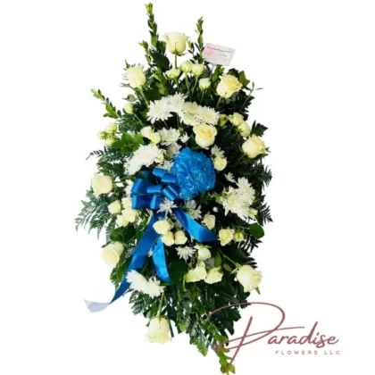 Serene Sky Memorial Standing Spray with white roses, spray roses, white cushion flowers, blue hydrangeas, and lush greenery, symbolizing tranquility and remembrance.