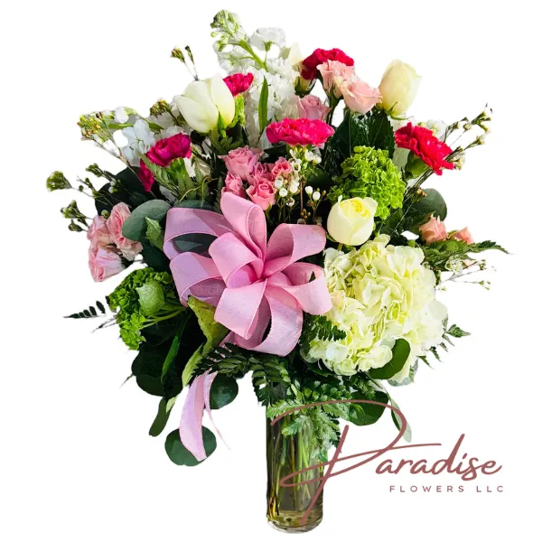 Sweet Mom Bouquet - Elegant arrangement of white roses, light pink spray roses, hot pink carnations, white stock, white hydrangea, green mini hydrangea, waxflower, and fresh greenery in a clear vase with a pink bow.