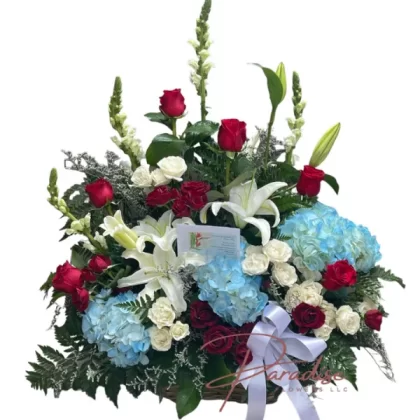 Tiny Treasure bouquet featuring white snapdragons, red roses, spray roses, blue hydrangeas, white lilies, and lush greenery.