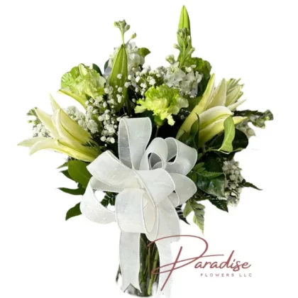 Whispering Peace floral arrangement featuring white stocks, lilies, green carnations, baby’s breath, and lush greenery.