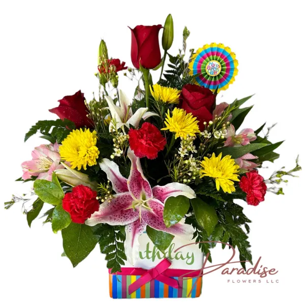 Joyful Celebration Bouquet featuring red roses, yellow daisies, red carnations, pink lilies, alstroemeria, waxflowers, and lush greenery in a 'Happy Birthday' ceramic vase.