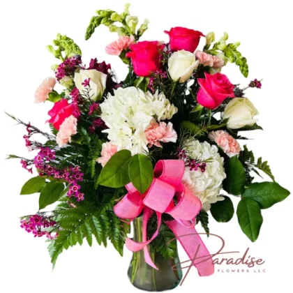 Healing Petals bouquet featuring hot pink roses, white roses, white snapdragons, pink carnations, waxflowers, and lush greenery in a stylish vase with a graceful bow.