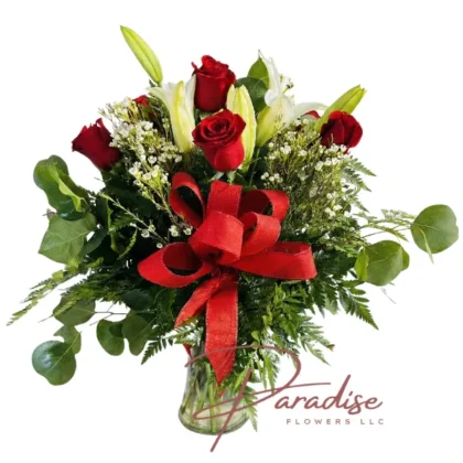 Eternal Kiss floral arrangement featuring 7 red roses, 4 white lilies, and a large red bow in a clear glass vase.