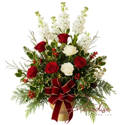 Royal Christmas Blooms arrangement with towering white stock, red and white roses, holly, and a red velvet bow in a gold vase.