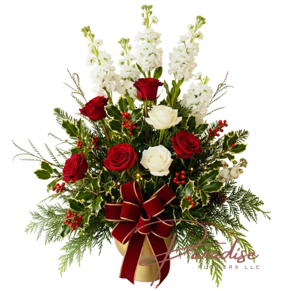 Royal Christmas Blooms arrangement with towering white stock, red and white roses, holly, and a red velvet bow in a gold vase.
